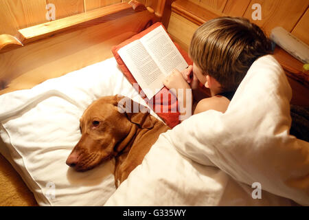 Startstelle, Österreich, ist junge mit seinem Hund im Bett und las ein Buch Stockfoto