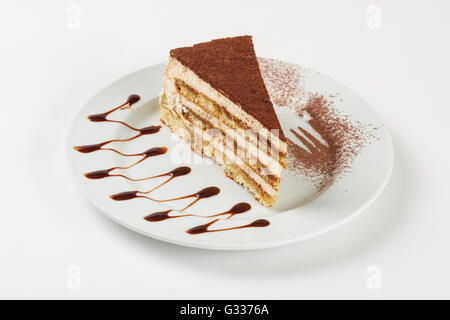 Köstliche Schokolade-Sahne-Torte auf dem Teller auf weißem Hintergrund. Schließen Sie die Seitenansicht. Stockfoto