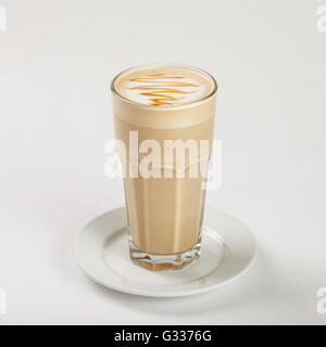 Leckeren Latte in ein hohes Glas auf dem Teller auf weißem Hintergrund. Schließen Sie die Seitenansicht. Stockfoto