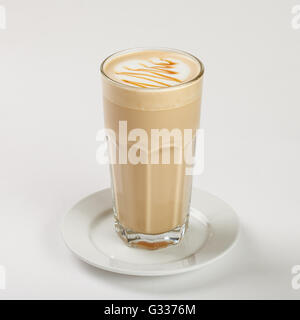 Leckeren Latte in ein hohes Glas auf dem Teller auf weißem Hintergrund. Schließen Sie die Seitenansicht. Stockfoto