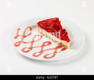 Lecker Käsekuchen mit Erdbeer-Gelee und Marmelade auf dem Teller auf weißem Hintergrund. Schließen Sie die Seitenansicht. Stockfoto