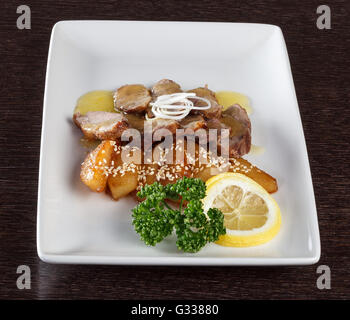 Fleischstücke zartes Kalbfleisch mit Soße, Bratkartoffeln und einer Scheibe Zitrone und Petersilie auf weißen Teller. Europäische Küche. Seite vi Stockfoto