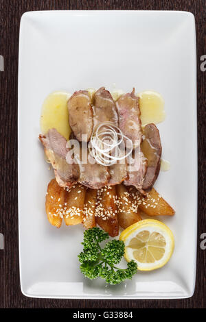 Fleischstücke zartes Kalbfleisch mit Soße, Bratkartoffeln und einer Scheibe Zitrone und Petersilie auf weißen Teller. Europäische Küche. Top vie Stockfoto