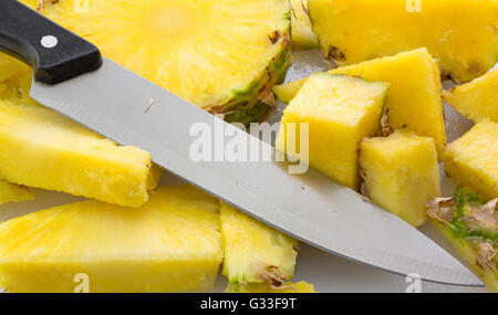 Eine frische Ananas auf ein Schneidebrett, die mit einem großen Messer in Scheiben geschnitten. Stockfoto