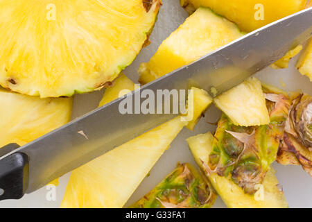 Eine frische Ananas auf ein Schneidebrett, die mit einem großen Messer in Scheiben geschnitten. Stockfoto