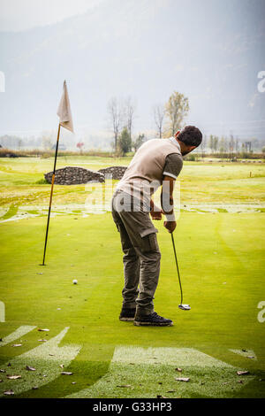 ein Golfspieler mit dem Ziel des Loches auf dem Grün mit dem putter Stockfoto