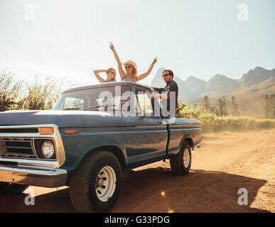 Gruppe von Menschen auf der Rückseite ein Pick up LKW Spaß. Junge Männer und Frauen genießen auf einer Straße Reise im Land an einem sonnigen Stockfoto