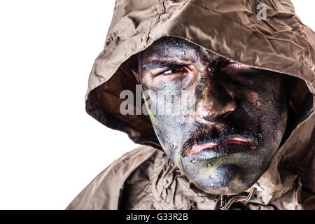 ein Soldat trägt einen Poncho oder Regenmantel und Armee Camouflage Gesicht malen auf einem weißen Hintergrund isoliert Stockfoto