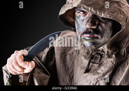 ein Soldat trägt einen Poncho oder Regenmantel und Armee Camouflage Gesicht malen Stockfoto