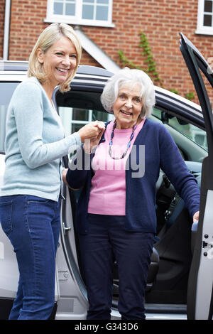 Weibliche Nachbarn geben Senior Woman A Lift im Auto Stockfoto