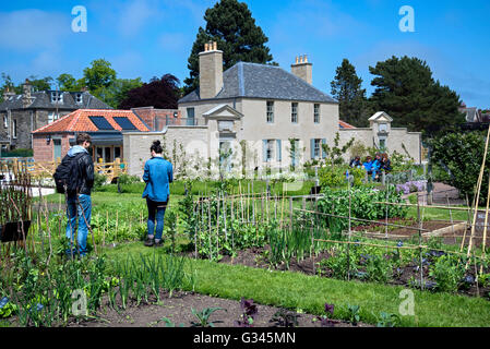 Besucher, die Royal Botanic Gardens in Edinburgh inspizieren Kraut und Gemüse Grundstücke mit dem botanischen Cottage im Hintergrund. Stockfoto