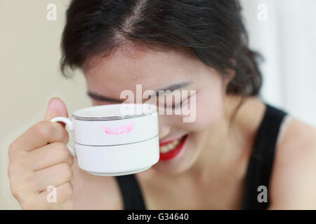 Eine glückliche asiatische Frau mit einer Tasse Kaffee Stockfoto