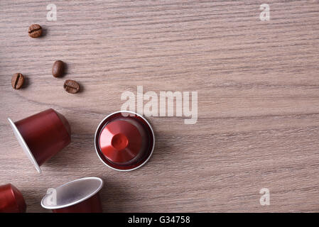 Drei Kapseln Espresso und Hülsen auf braunen Holztisch. Ansicht von oben Stockfoto