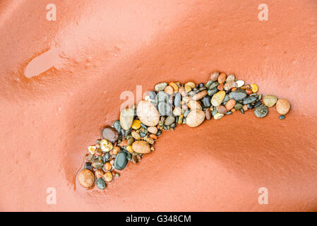 Bunte Kieselsteine in einem hohlen Welle geformt Sandstein an der Fleswick Bucht unter St. Bees Head Cumbria Stockfoto