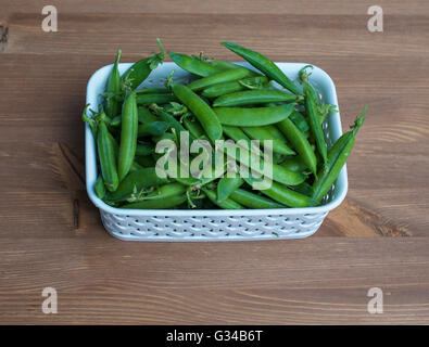 Viele grüne Erbsen in einem weißen Korb auf den Tisch Stockfoto