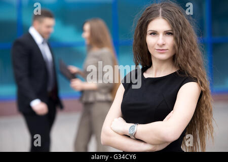 Porträt der selbstbewusste junge Frau mit verschränkten Armen und ernsten Gesichtsausdruck, Blick in die Kamera im freien Stockfoto