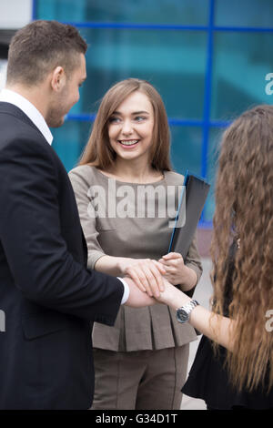 Erfolgreiche glücklich Geschäftsleute, Hand in Hand zusammenarbeiten. Lächelnde Geschäftsfrau im Mittelpunkt. Erfolgreiches Konzept Stockfoto