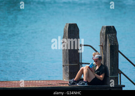 Aberystwyth Wales UK, Mittwoch, 8. Juni 2016 UK Wetter: eine Frau liest ihr Buch über das Meer Steg an einem schönen sonnigen und sehr warmen Tag in Aberystwyth auf West Wales Küste Photo Credit: Keith Morris / Alamy Live News Stockfoto