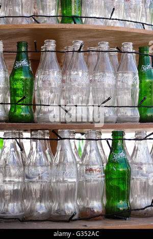 Paphos, Zypern - leere 11. Dezember 2015 Flaschen Coca Cola und Sprite stehen in Reihen auf Holzregalen mit Lichtern. Stockfoto