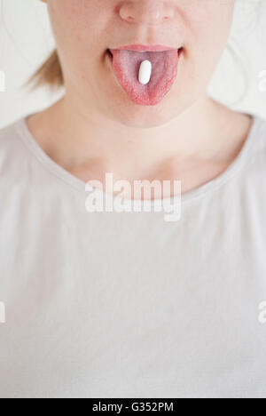 Frau mit einem weißen Pille auf ihrer Zunge Stockfoto