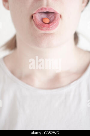 Frau mit Pille auf ihrer Zunge Stockfoto