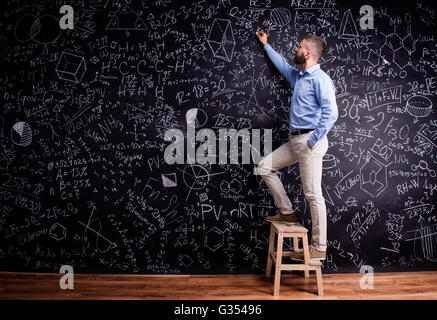Mann schreiben an große Tafel mit mathematischen Symbolen Stockfoto