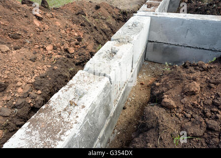 Graue Bau konkrete Bausteine für die Fundamente eines selbst gebauten Hauses verwendet. Aushub und ausgegraben Erde surround Stockfoto