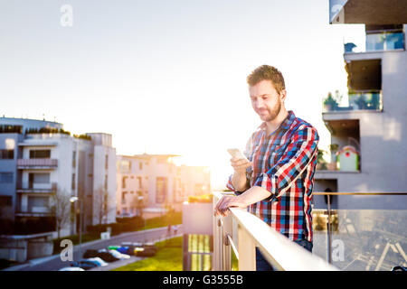 Hipster Geschäftsmann mit Smartphone SMS, stehend auf balcon Stockfoto