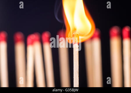 Brennendes Streichholz vor eine Reihe neuer Spiele. Stockfoto