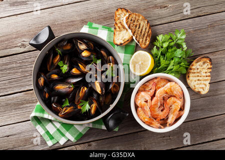 Muscheln und Garnelen mit Brot Toasten auf Holztisch. Ansicht von oben Stockfoto