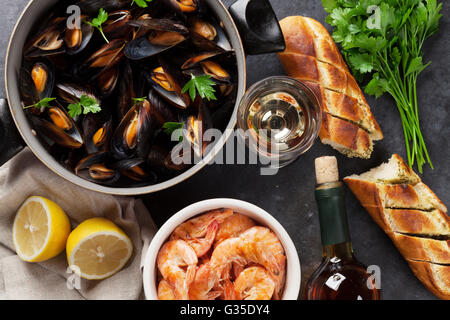 Muscheln, Garnelen und Weißwein auf steinernen Tisch. Ansicht von oben Stockfoto