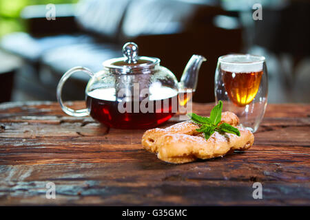 Leckere Eclair und Tasse Tee auf Holztisch Stockfoto