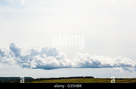 Schicht der niedrigen grauen Cumulus-Wolken bilden über Felder und nach Gelände gegen bedecktem Himmel. Stockfoto