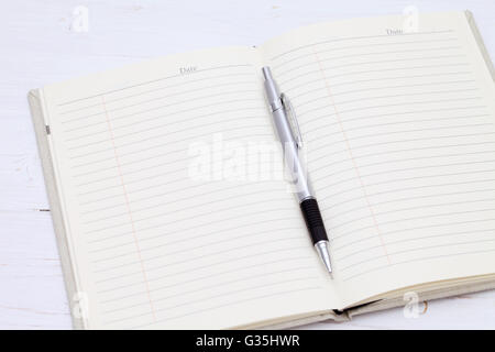 Notizbuch mit Stift auf dem weißen Holztisch Stockfoto