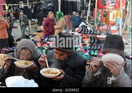 CHINA, Provinz Xinjiang, Markttag in der uigurischen Dorf Jin Erek in der Nähe der Stadt Kashgar, wo der Uiguren leben Leute, alte Menschen essen Nudelsuppe mit Stäbchen Stockfoto