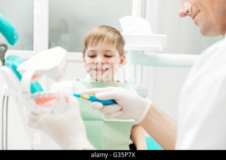 Zahnarzt wie kleine Junge Lehre zur Zahnreinigung in Zahnklinik Stockfoto