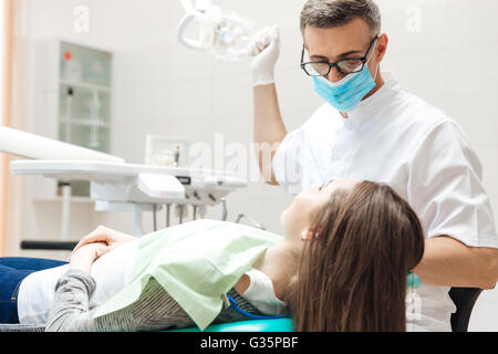 Zahnarzt sehr sorgfältig prüfen und reparieren Zahn seine junge Patientin in der Klinik Stockfoto