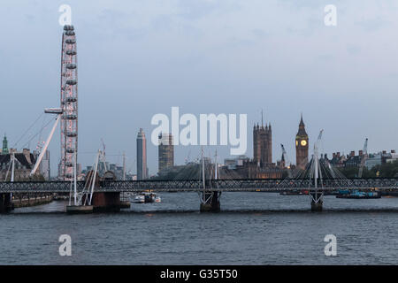 Die Themse bei Einbruch der Dunkelheit mit den Houses of Parliament in der Ferne, das London Eye links und Hungerford Bridge Stockfoto