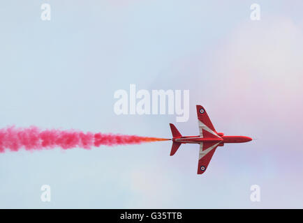 RAF Red Arrows Flugzeug geradeaus fliegen, mit farbenfrohen roten Rauch, Duxford Airshow, Cambridgeshire UK Stockfoto