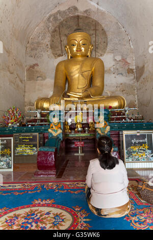 Frau, die neugierigen an der Vorderseite eine kunstvolle Statue von Buddha im Tempel, alte Tempel-Architektur, Myanmar, Burma, Südasien, Asien Stockfoto