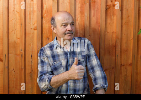 Älterer Mann mit einem Schnurrbart und einem kahlen Kopf billigt die Wahl. Zeigen Daumen nach oben. Stockfoto