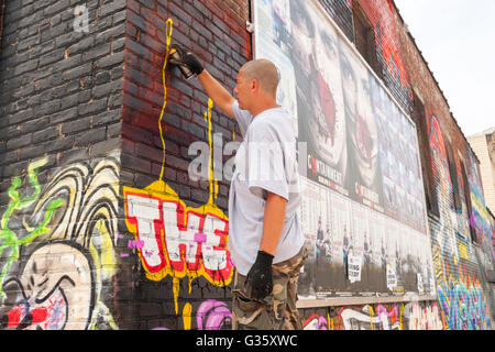 Jerms arbeitet an seinem Wandbild in Bushwick, Brooklyn in New York während der jährlichen Bushwick kollektive Block Party am Samstag, 4. Juni 2016. Musik und Party brachte einige, aber die eigentliche Attraktion war die neue Wandmalereien von "" Graffitikünstler, die die Wände der Gebäude schmücken, die das Kollektiv verwendet.  (© Richard B. Levine) Stockfoto