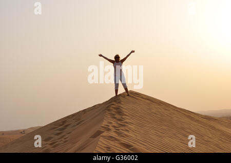 Mädchen, Person, Frau auf der Sanddüne Hallo winken. Auf Wiedersehen, Dubai VAE, Sonnenuntergang oder in der Sonne steigen, Cool der Wüste. Silhouette in der Wüste Stockfoto