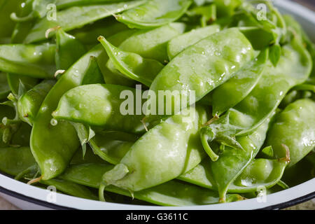 eine Schüssel mit rohem, frisch, Zucker-Snap Erbsen in ihren Hülsen Stockfoto