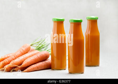 Drei Flaschen Karottensaft mit Karotten. Selektiven Fokus. Stockfoto