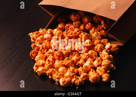 viele Popcorn in eine Papiertüte auf dunklem Hintergrund Stockfoto