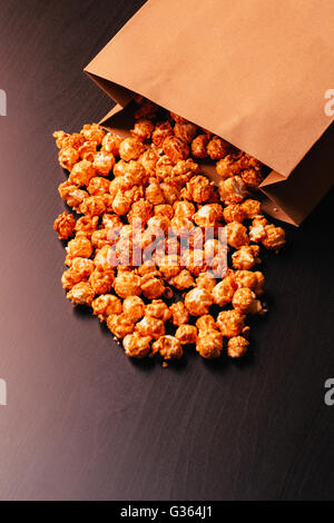 viele Popcorn in eine Papiertüte auf dunklem Hintergrund Stockfoto