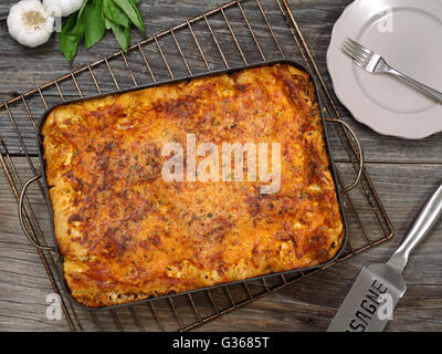 Foto von einem frisch gebackenen Lasagne, sitzen auf einem alten Holztisch. Stockfoto