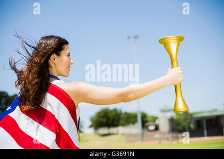 Sportlerin, eingehüllt in amerikanische Flagge mit Feuer Fackel Stockfoto