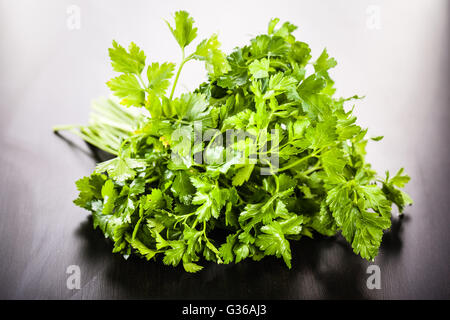 ein Haufen lebendige grüne Petersilie auf einer dunklen Holzoberfläche Stockfoto